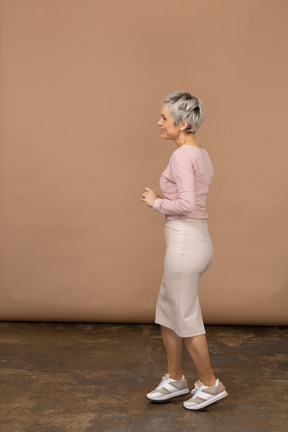 Vista lateral de una mujer feliz en ropa casual caminando