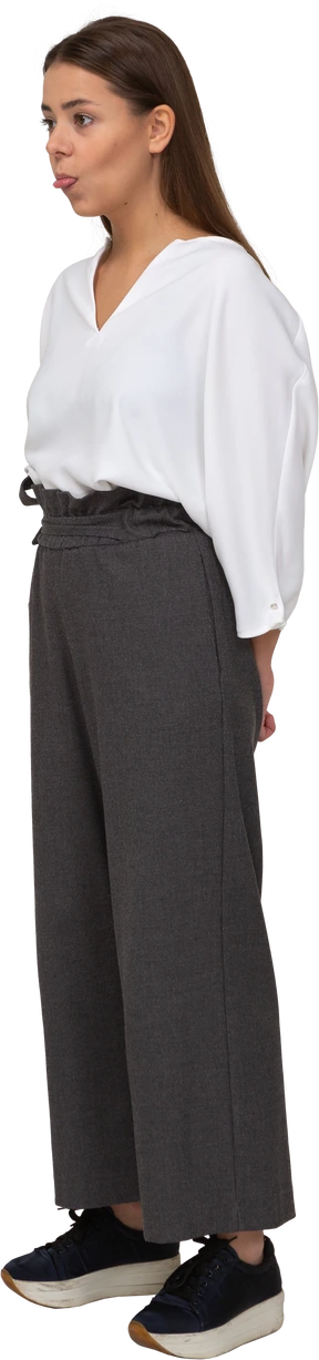Three-quarter view of a young lady in office clothing holding hands behind and showing tongue