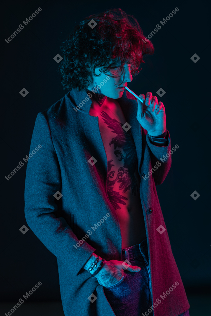 Young man smokes under neon lights