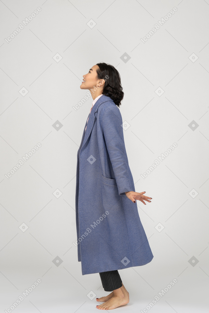 Вид сбоку женщины в пальто, смотрящей вверх