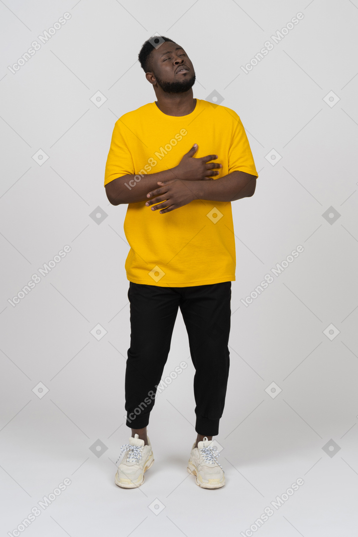 Front view of a young dark-skinned man in yellow t-shirt holding hands on stomach