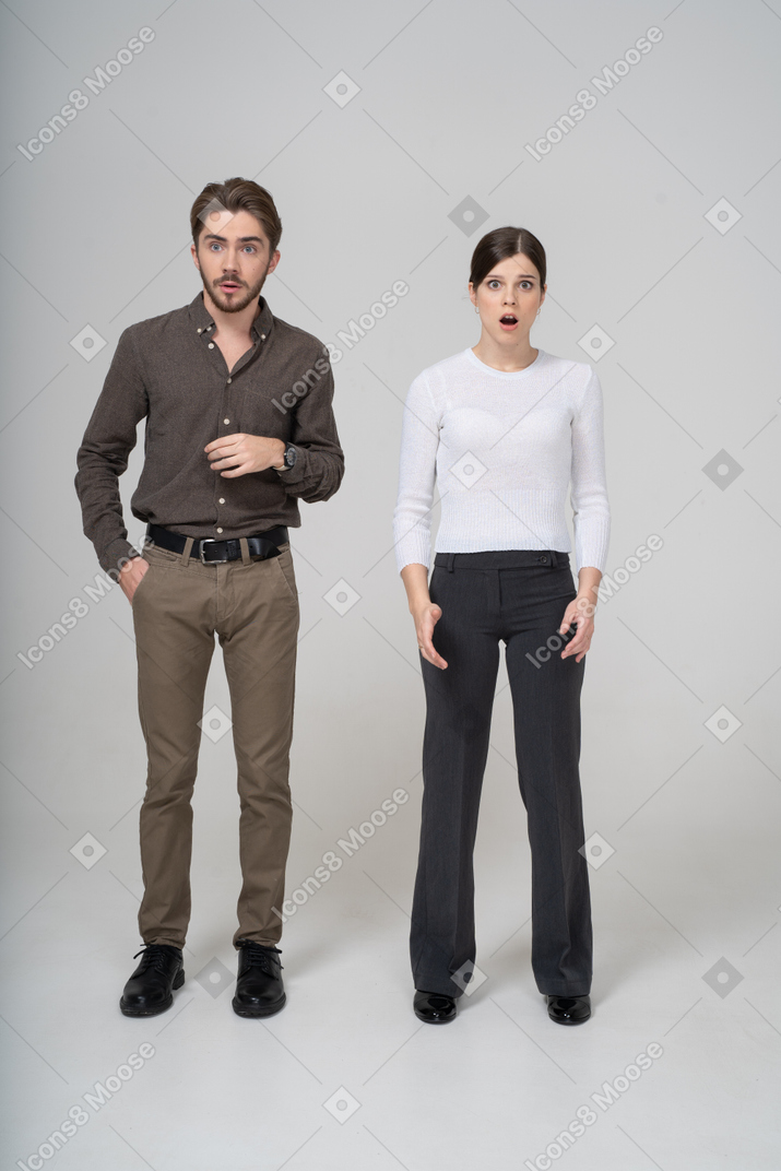 Front view of a shocked young couple in office clothing