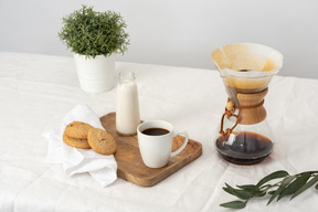 Chemex, taza grande de café, botella de leche, galletas y botella de leche.