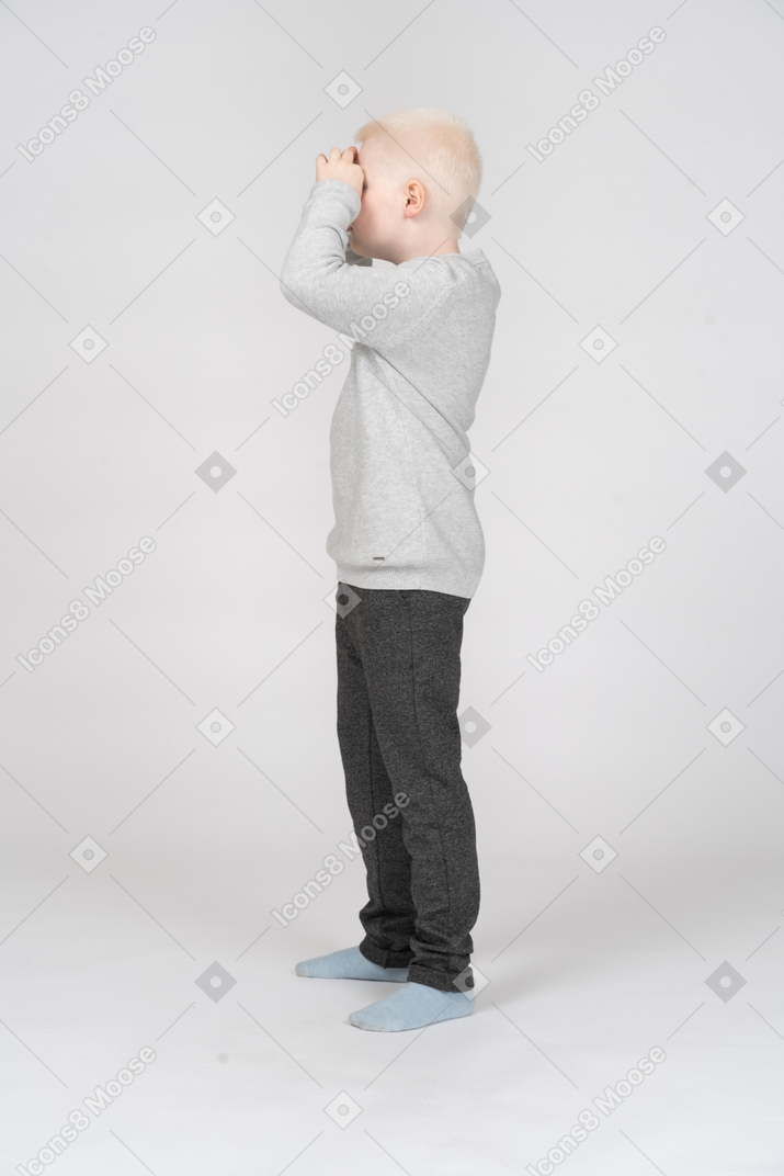 Side view of a boy looking at something through imaginary binoculars