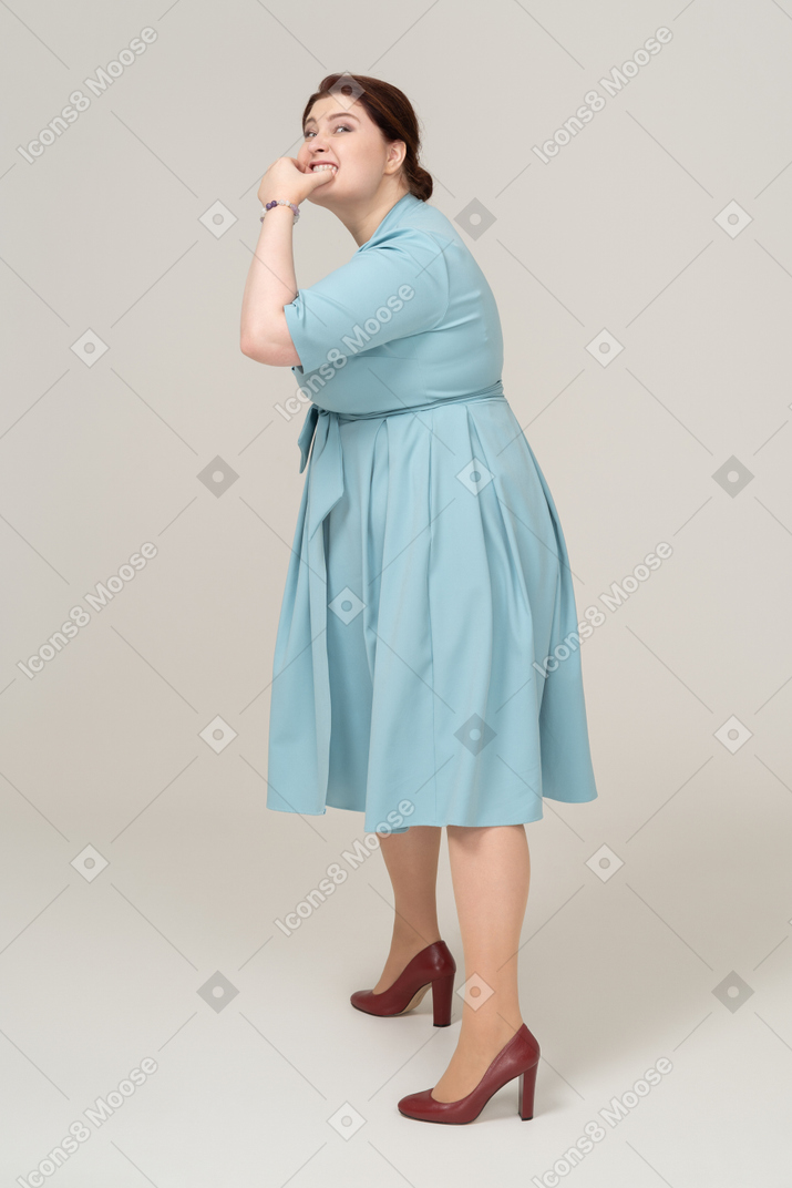 Side view of a woman in blue dress whistling