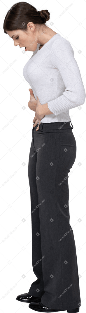 Vue latérale d'une jeune femme en vêtements de bureau touchant l'estomac