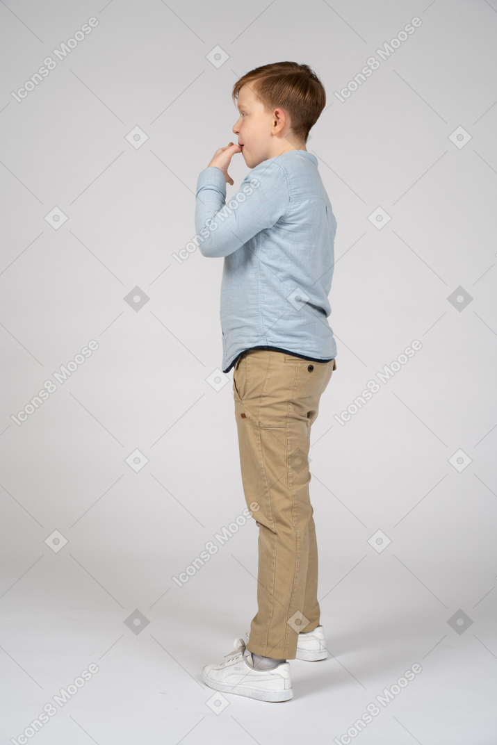 Cute boy standing in profile and whistling