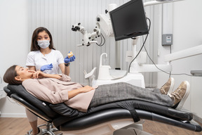 Comprimento total de uma dentista mostrando protótipo de dentes para paciente em um gabinete de hospital