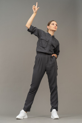 Front view of a young woman in a jumpsuit outstretching her arm