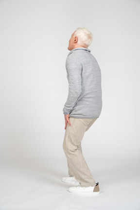 Side view of a man standing and touching his knee