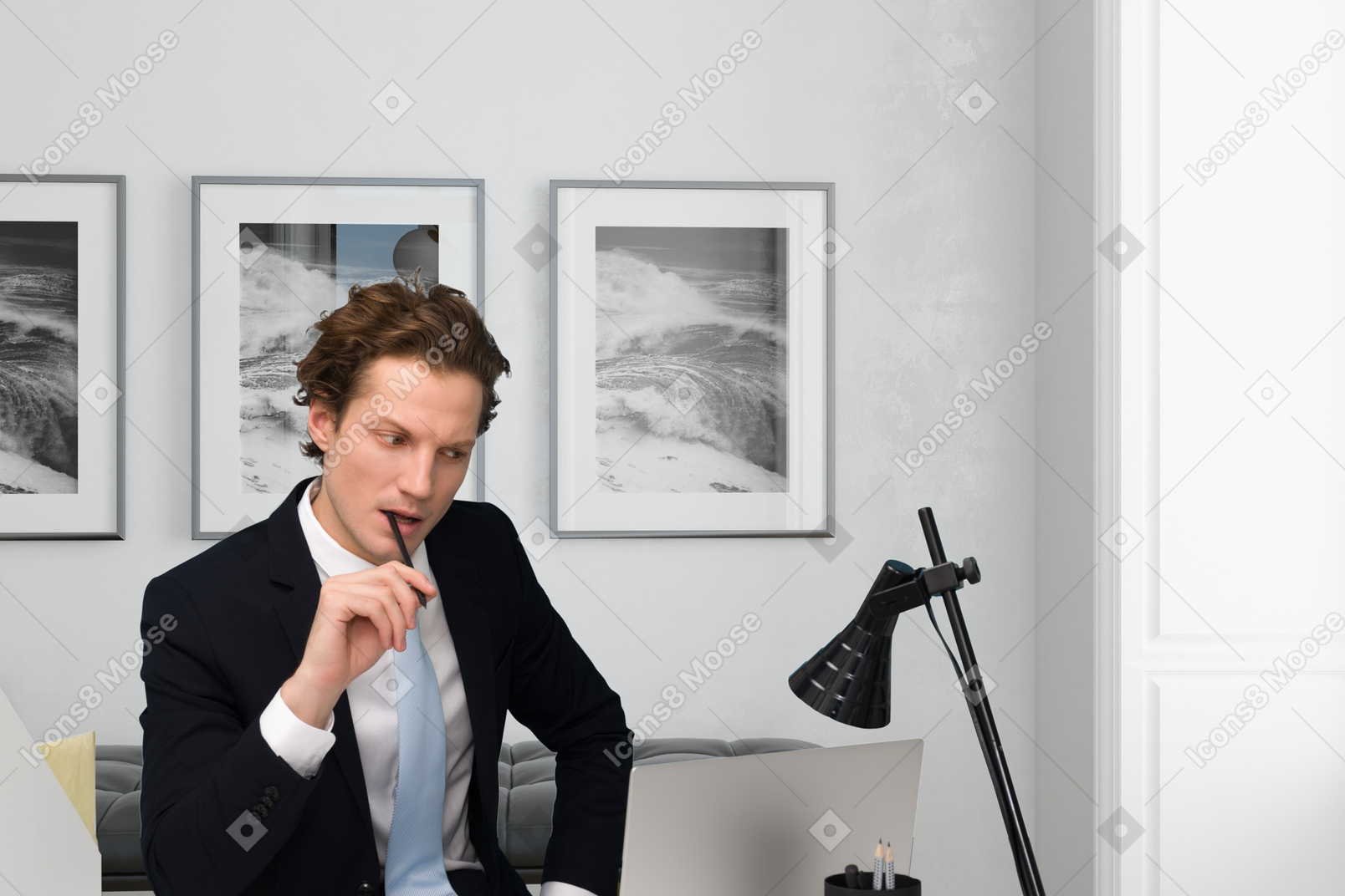 ノートパソコンを持って机に座っているスーツを着た男