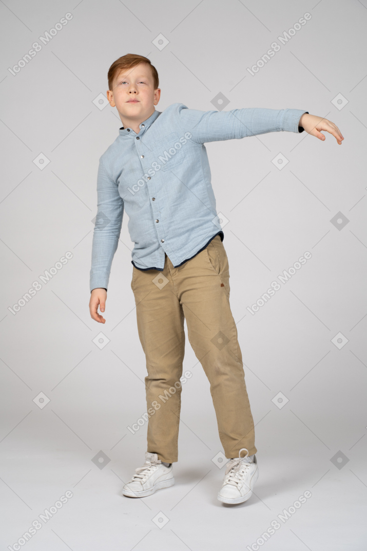 Boy in pants and shirt extending his left arm