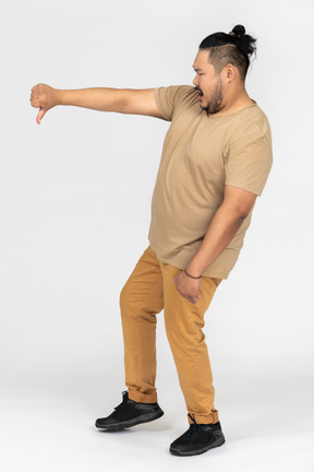 Expressive asian man showing thumb down