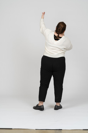 Vista posteriore di una donna grassoccia in abiti casual con il braccio alzato