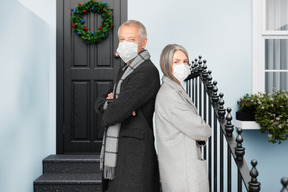 Senior socially responsible couple near a christmas decorated door