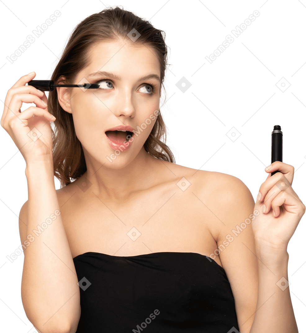 Vista frontale di una giovane donna sorpresa che indossa un top nero che applica mascara