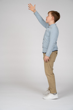 Boy in shirt and pants reaching up