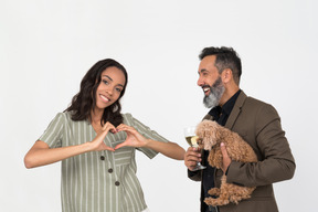 Afrowoman showing heart with hands to her hispanic partner which holding a puppy
