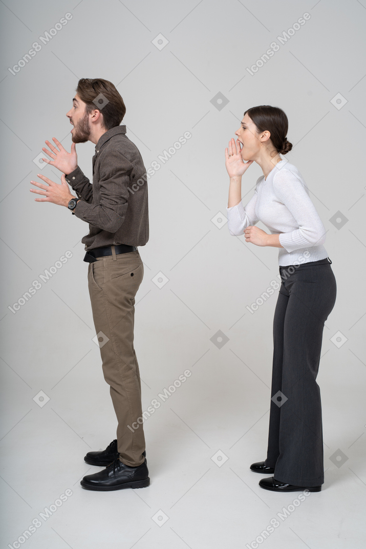 Side view of an emotional gesticulating young couple in office clothing