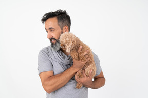 Handsome mature man standing in profile and holding a puppy