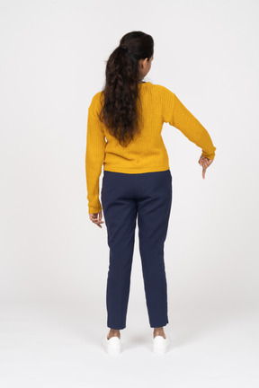 Rear view of a girl in casual clothes pointing down with a finger