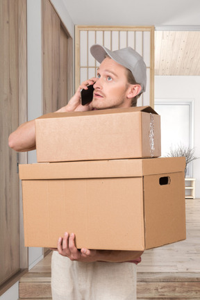 A man holding a box and talking on a cell phone