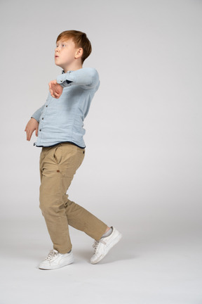 A young boy walking with his elbow raised