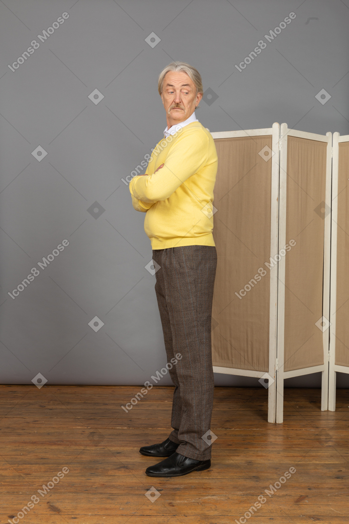 Side view of a curious old man crossing hands and looking aside