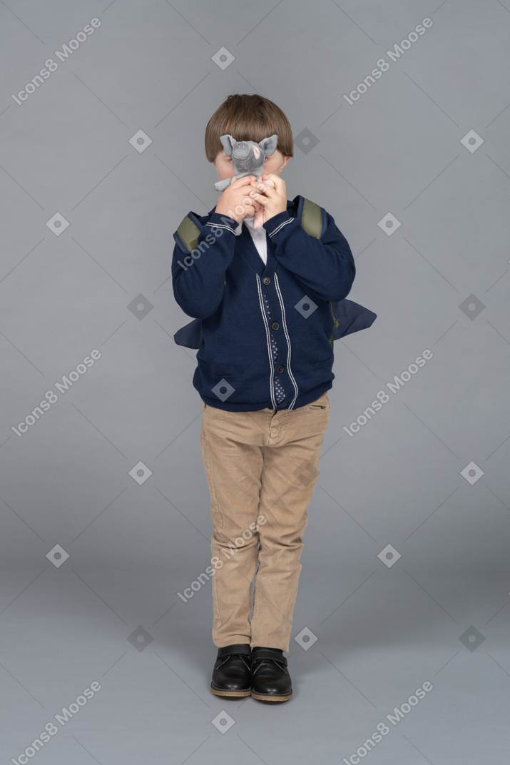 Little boy hiding his face behind a plush toy