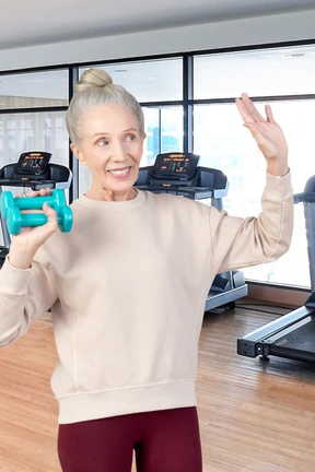 A woman in a gym holding up a pair of dumbs