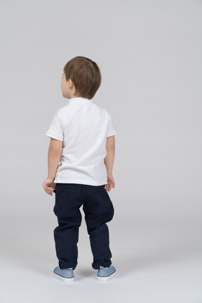 Little boy standing with his back toward the camera
