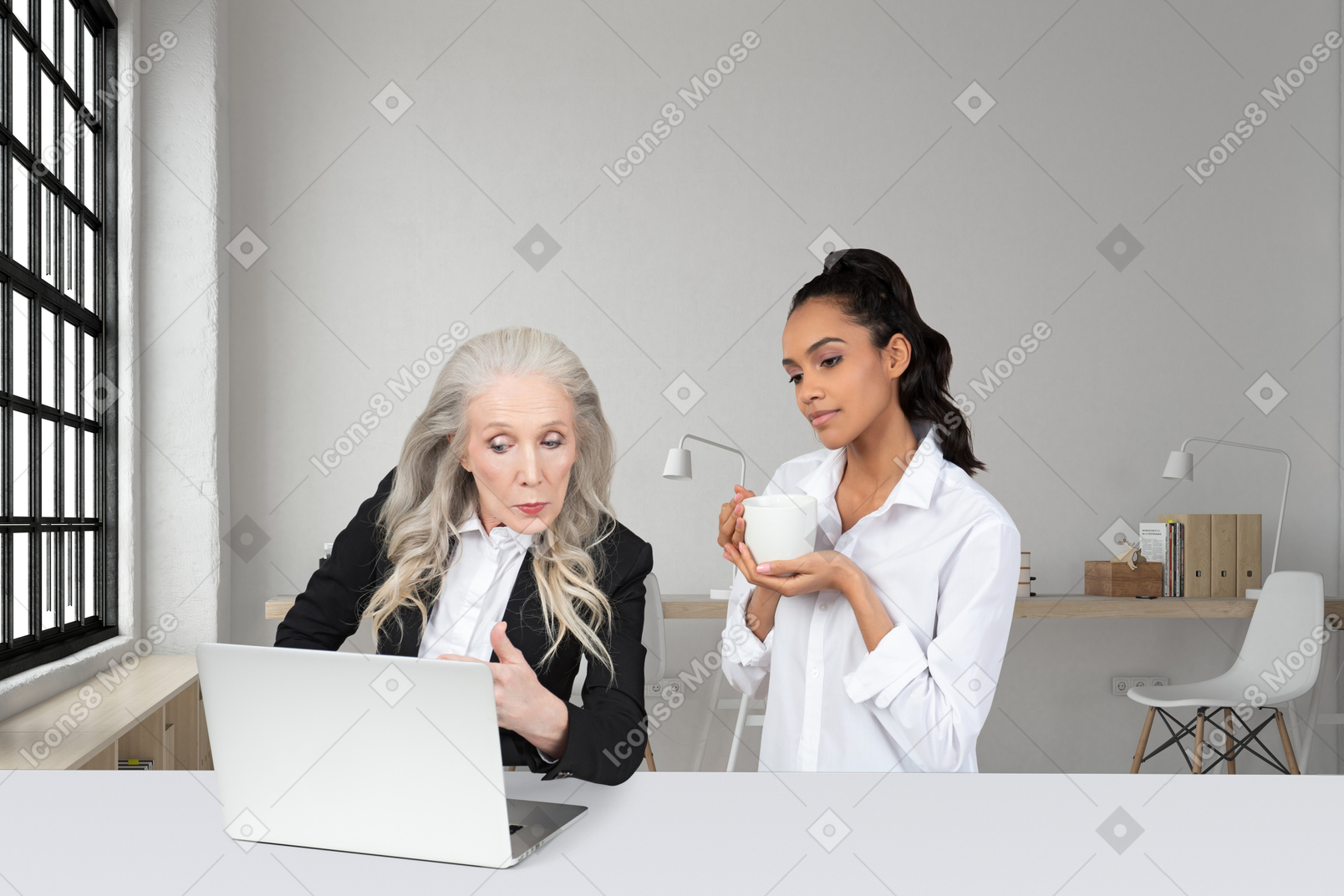 Two women sitting at a table looking at a laptop