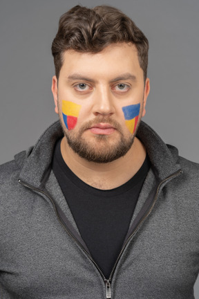 Front view of a male football fan with colorful face art