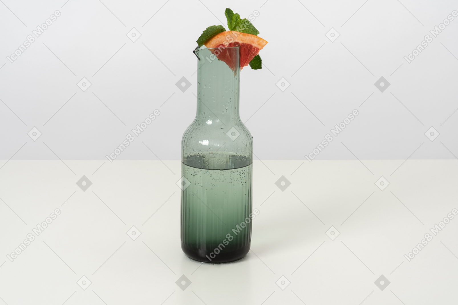 A glass bottle of cold water with a slice of a grapefruit and some mint on top of it, aka the best thing ever on a hot summer day