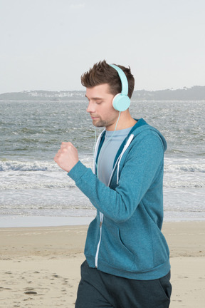 A man running on the beach with headphones on