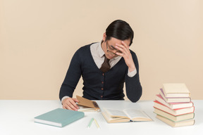 Young asian student in a sweater holding his head