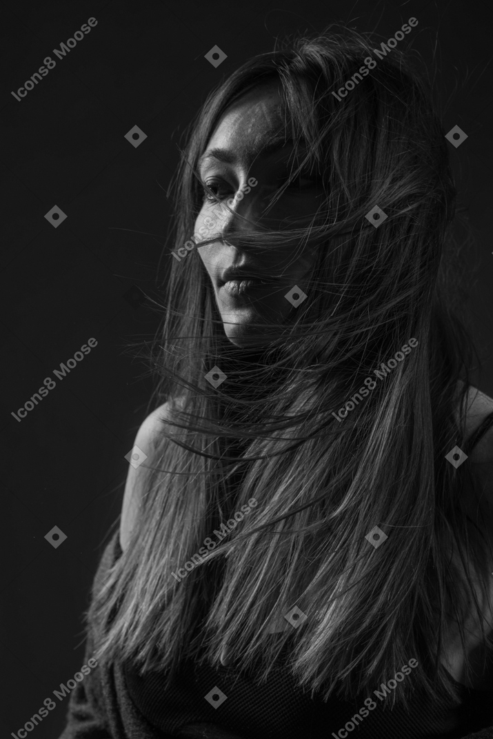 Noir three-quarter portrait of a young female with ethnic ornaments on her face and messy hair