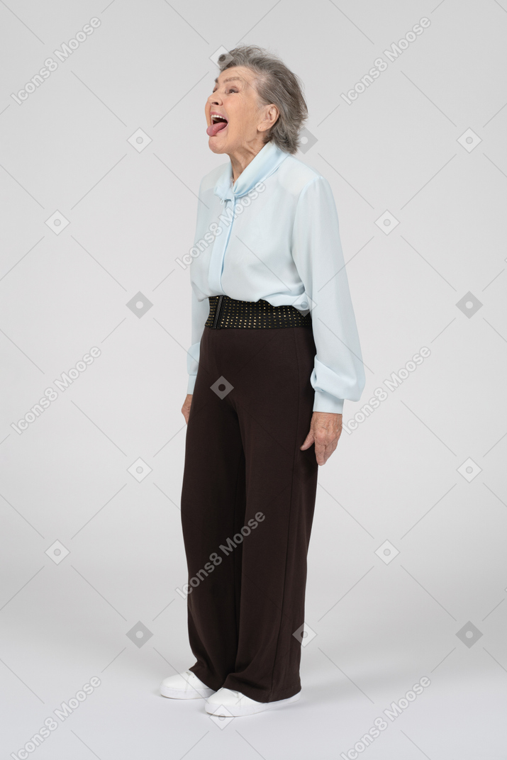 Vista lateral de una anciana sacando la lengua al estilo rock