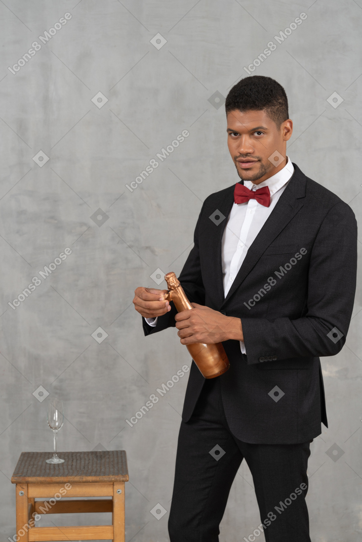 Uomo che rimuove l'involucro di alluminio da una bottiglia di champagne