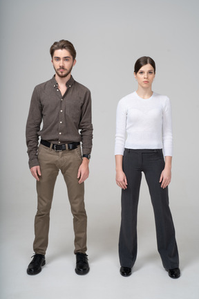 Front view of a young couple in office clothing standing still