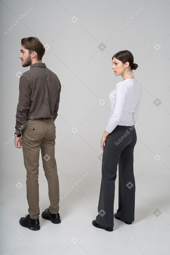 Vista de tres cuartos de una pareja joven en ropa de oficina de pie todavía