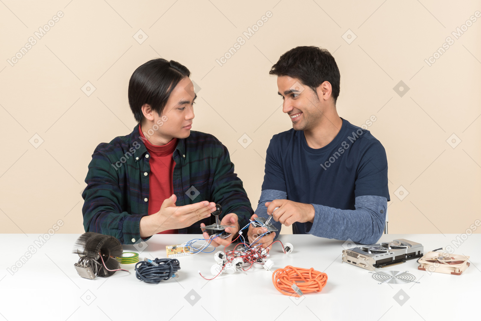 Two young geeks sitting at the table and fixing some details