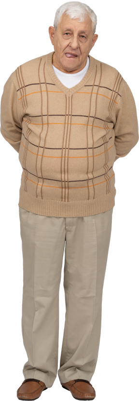 Vista frontal de un anciano con ropa informal que muestra la lengua