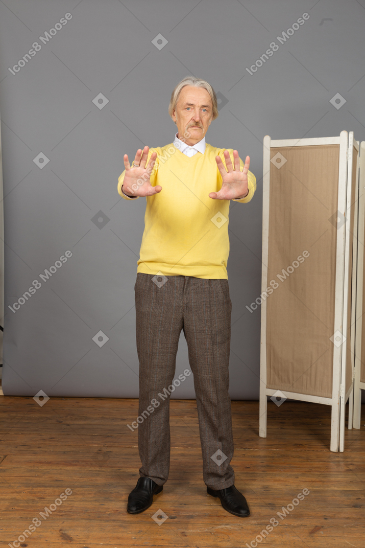 Vista frontal de un anciano disgustado extendiendo su mano