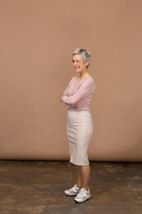 Vista lateral de una mujer en ropa casual de pie con los brazos cruzados.