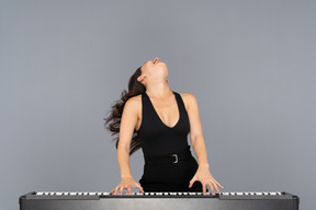 Mujer inclinando la cabeza hacia atrás mientras toca un piano