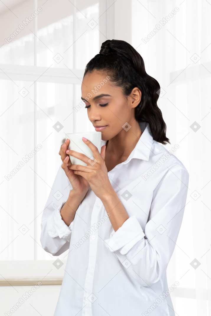 カップでお茶の臭いがする若い女性