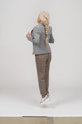Side view of an old lady in suit jumping
