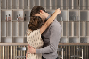 A man and a woman hugging in front of a bar