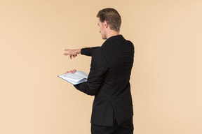 A white man in a fully black suit holding the quran